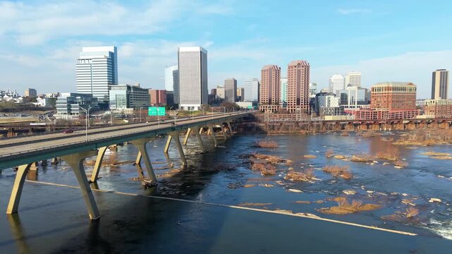 Richmond, Virginia skyline featuring the Manchester Bridge crossing the James River rapids into the downtown financial district. 4k aerial cinematic video.