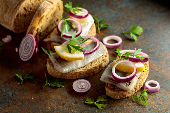 Open sandwiches with herring filet, red onion, lemon, and parsley.
