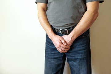Senior man in jeans holding his crotch with prostate problems