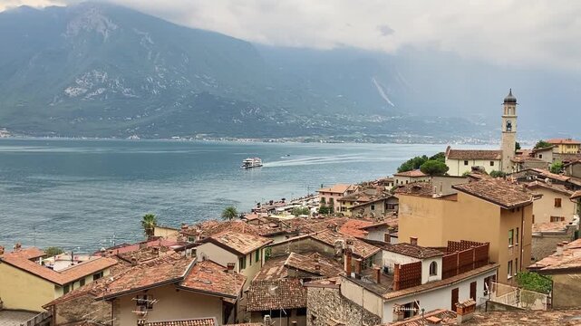 Limone sul Garda, Itlay, narrow houses and church, Garda lake view with Ferry boat and passing small Airplane