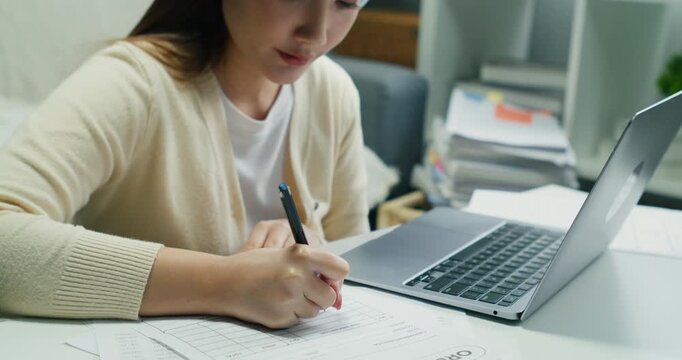 A busy woman achieving business success. She is reviewing a digital document for finance planning in her interior workspace.