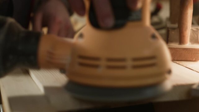 An electric orbital sander expertly polishes a wooden surface, removing imperfections and refining the material. The tool diligently works to achieve a perfectly smooth and prepared finish.