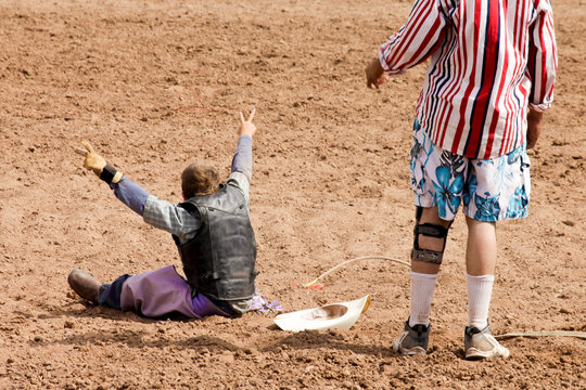 Galisteo, New Mexico, United States.Rodeo clown approaching young rider after fall in arena
