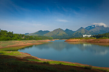 Obraz premium Scenic reflection of green peaks in a tropical reservoir under bright sunlight.