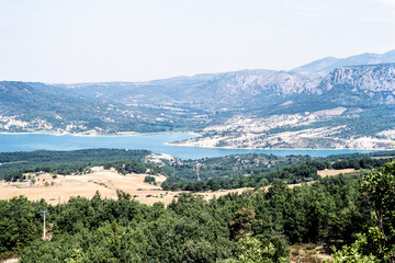 Naklejka premium Verdon lake landscape near Gréoux-les-Bains, Alpes-de-Haute-Provence, France, 8 August 1986: wide panoramic view of turquoise water, mountains and rural countryside in Provence