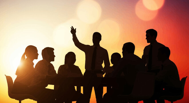 Silhouette of business meeting at sunset, leader speaking to team around table