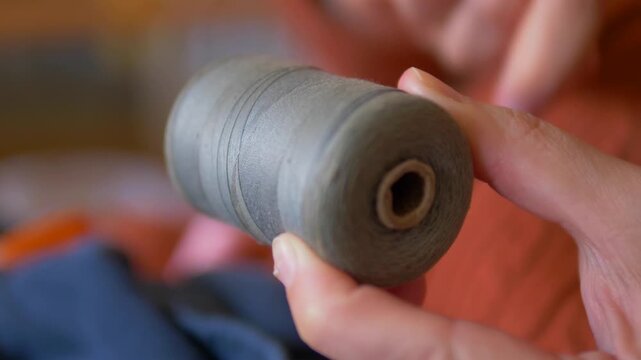 Hands Holding Large Spool of Grey Yarn End-On During Knitting or Weaving Session at Home &mdash; Textile Craft, Slow Living, Handmade and Creative Hobby Concept