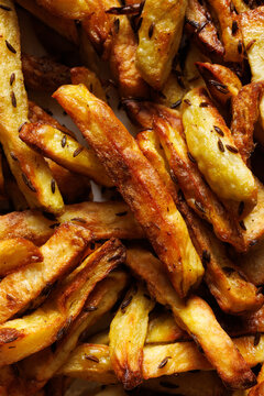 Homemade potato French fries baked in the oven with aromatic spices, close-up view. French fries background