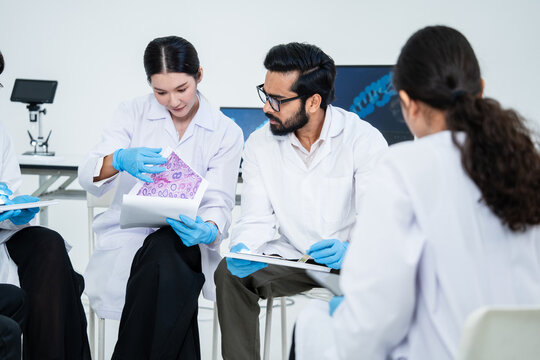 Group of diverse medical scientists in lab coats discussing pathology biopsy results on printed reports in a clinical lab setting. Professional team analyzing diagnostic data together