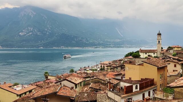 View of Limone sul Garda, Italy, old town buildings, Garda Lake with ferry boat