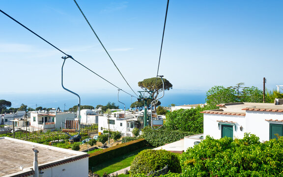 Chairlift in Anacapri at Capri Island, Italy. Cable car equipment with scenic background of buildings, greenery and sea. Chairlift in Anacapri is way to get to summit of Monte Solaro 