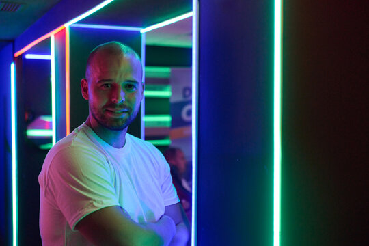 Confident Man Portrait in Neon Lights at Nightclub With Arms Crossed and Casual White T Shirt