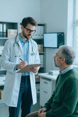Vertical shot of male doctor reviewing notes on clipboard while senior man attending medical consultation in clinic. Useful for healthcare services, patient care, diagnosis, insurance