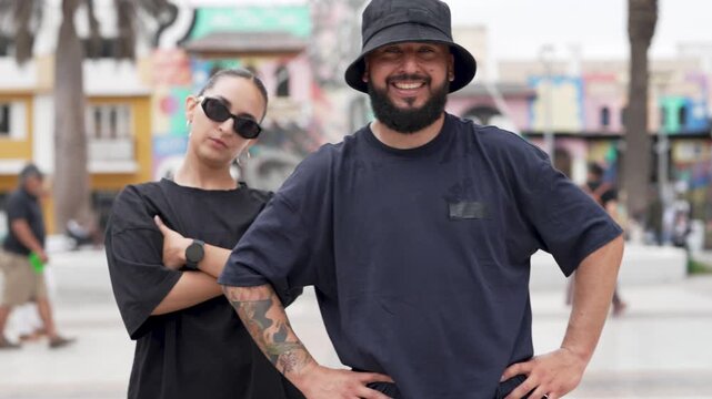 Stylish man and woman performing a modern dance, smiling and posing for the camera on a city street