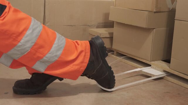 An industrial safety topic. A worker in danger of tripping over a piece of plastic strapping in a factory.