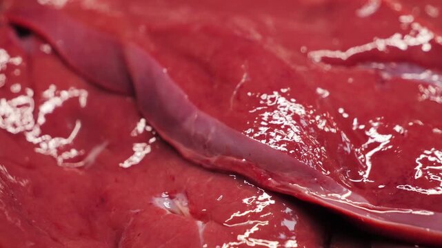 Close-up texture of raw beef liver cut into slices. Fresh organ meat prepared as steaks, detailed food texture. High quality 4k footage