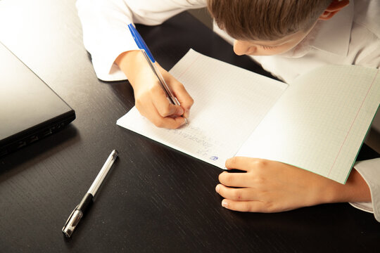 Close-up of a child writes in a notebook. 