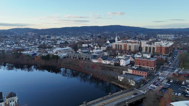 Aerial backward reveal of a small waterfall along the Charles River near Waltham Massachusetts in autumn
