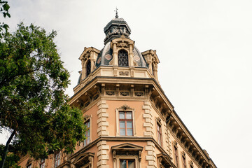 Fototapeta premium Skyward Ornate Corner Tower And Balcony, Urban Vantage, Planner Sketches Facade Restoration, Leafy Tree Frames