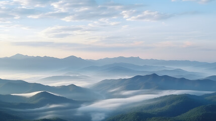 Obraz premium A serene mountain landscape shrouded in mist and fog at sunrise where the morning sun glows over a blue forest valley and distant snowy peaks under a cloudy sky