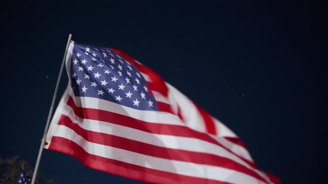 Waving American flag close up at night in Malibu, California, USA with strong lighting and wind movement creating emotional patriotic tribute scene
