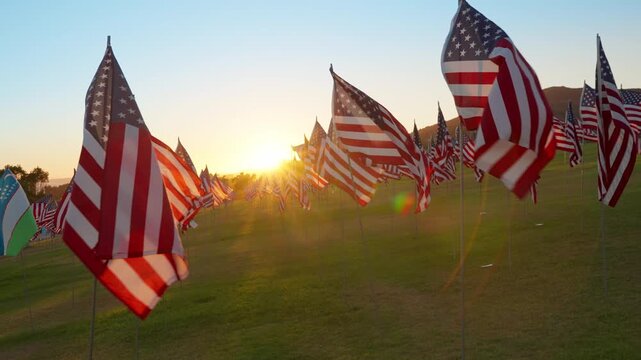 American flag field at sunset in Malibu, California, USA honoring September 11, warm golden light and moving flags creating powerful patriotic and emotional visual scene. Slow motion