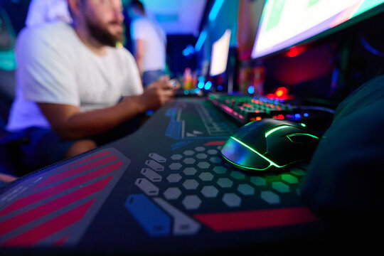 Gamer Using RGB Gaming Mouse And Keyboard At LAN Party With Console Controller And Monitors
