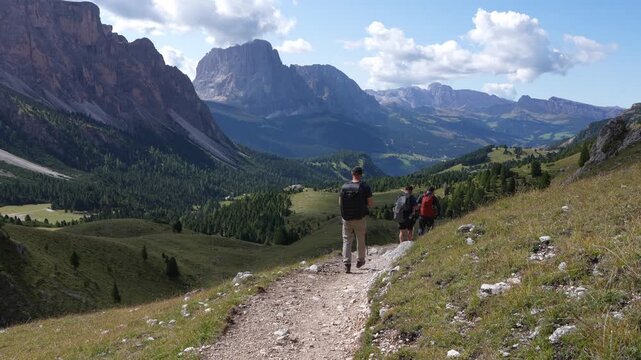 Hikers on the mountain trail in  Puez - Odle National Park. In the background, the Langkofel mountain massif. Italy. Dolomites.