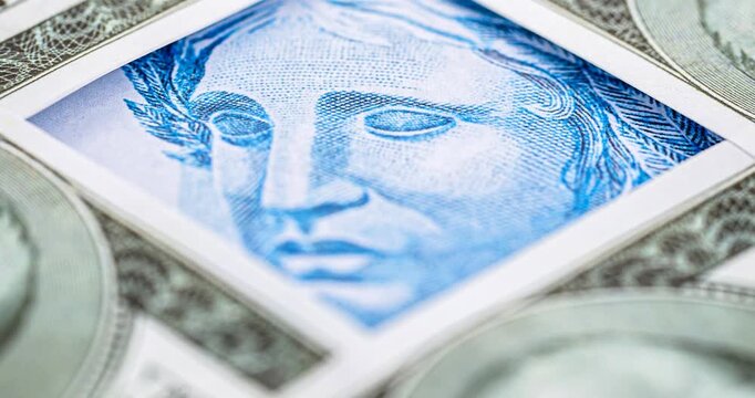 Detail video of a Brazilian one-hundred-real note, next to one-hundred American dollar notes. Economic crisis and rise in the American currency, rise or fall of the dollar in reference to the Brazilia