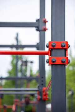 Detailed close up of red steel bolt and metal structure for outdoor fitness station in city park. Sport equipment construction for workout. Calisthenics facility for exercise training.