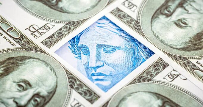 Detail video of a Brazilian one-hundred-real note, next to one-hundred American dollar notes. Economic crisis and rise in the American currency, rise or fall of the dollar in reference to the Brazilia