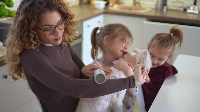 Mother and daughters cleaning a dog with a lint remover roller