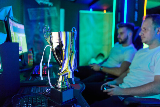 Esports Trophy on Desk With Gamers Competing in Late-Night Video Game Tournament