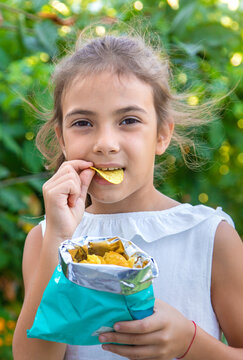 The child is eating chips. Selective focus.