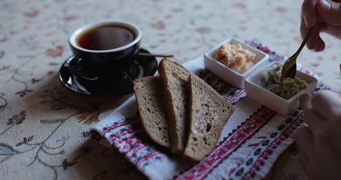 Person spreading butter on rye bread during breakfast in a cafe