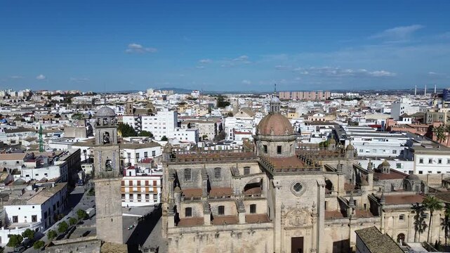 Aerial drone shot moving backwards in 4K resolution revealing a panoramic view of the Jerez Cathedral bell tower and the old town district under a clear sunny sky