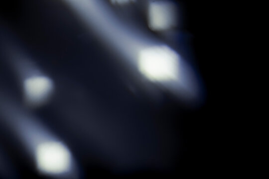 Blue light flare prism rainbow flares overlay effect on black background, light crossing crystals, prismatic sun catcher reflections rays. Abstract blurred colourful lens flare bokeh on dark backdrop