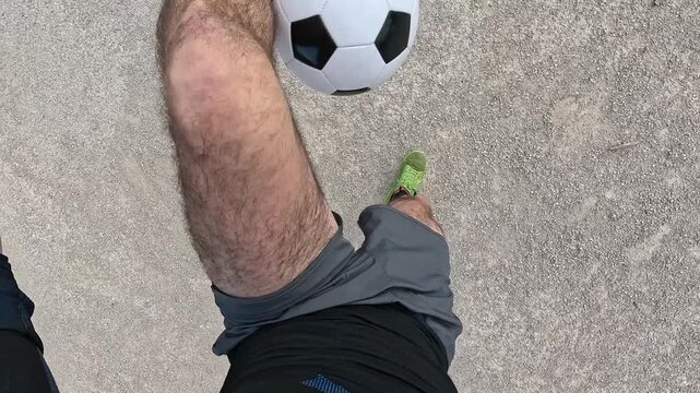 Man performing soccer freestyle tricks, juggling and controlling a football with his feet. First person pov of athletic skill and practice