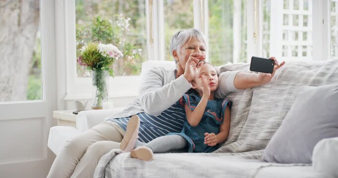 Home, child and grandma with smartphone for video call, happy and communication with contact on sofa. Hello, wave and senior woman with girl in lounge, bonding or excited for virtual chat with mobile