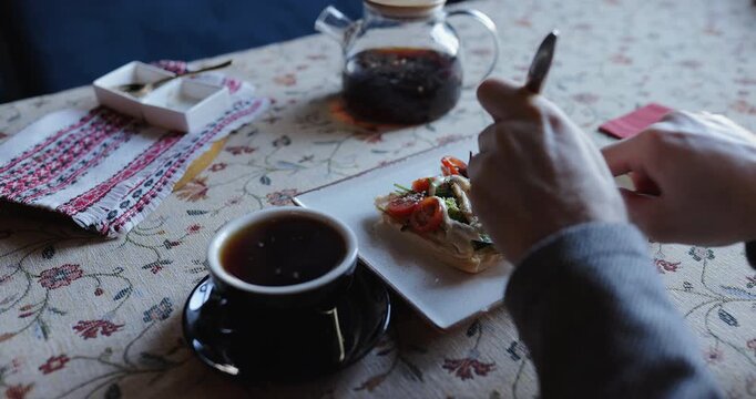 Person eating healthy bruschetta with vegetables and chicken in a cafe