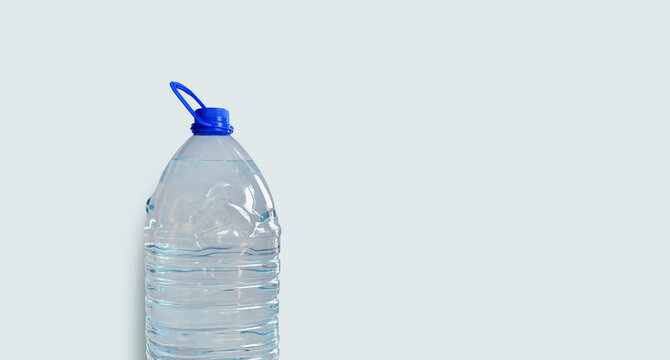 Drinking water bottle, isolated on light blue backdrop. Transparent plastic 5l bottle, full, blue cap. Clean water supply concept. Horizontal studio shot