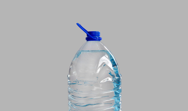Plastic bottle with drinking water, isolated on grey backdrop. Transparent 5l bottle, full, blue cap. Clean water supply concept. Horizontal studio shot