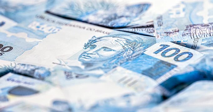 details of banknotes of 100 reais from brazil, and brazilian coins, with selective focus, background image. Promotion concept or grand prize money.