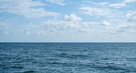 Obraz premium mild ocean scene presenting calm sea surface and cloud-speckled sky