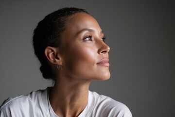 Obraz premium Studio-side profile photograph of a woman with imagined flight mood, white t-shirt, clean gray background