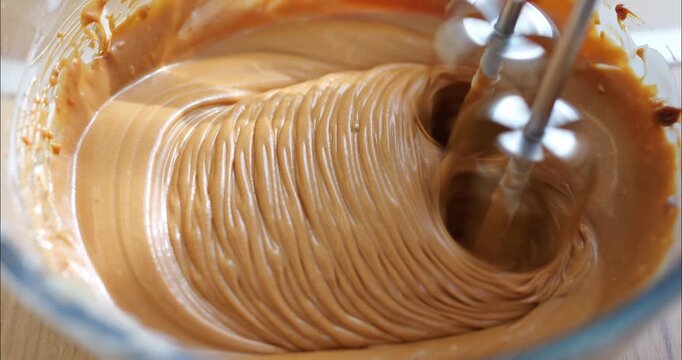 Beat the cream for the cake with a mixer. Confectionery mixture for greasing the cakes.