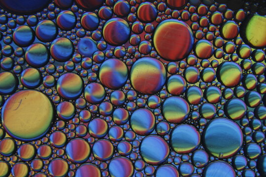 Burbujas coloridas abstractas de aceite y agua que crean un fascinante patr&oacute;n, con vista cercana de gotas de aceite iridiscentes flotando en el agua, formando un fondo abstracto vibrante y din&aacute;mico