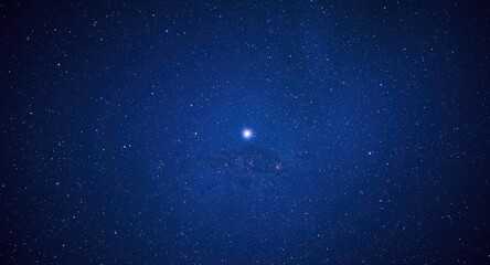 Fototapeta premium Faraway planet illuminated by a vibrant blue sky filled with shimmering stars