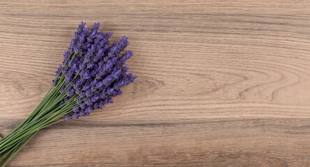 Obraz premium Lavender bunch lying on natural wood grain background including copy space