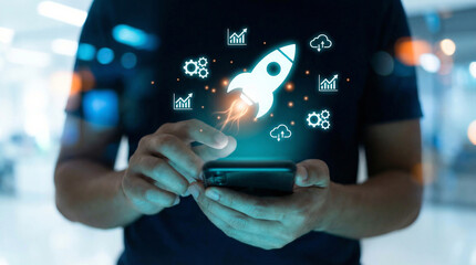 Fototapeta premium A person holds a smartphone displaying a glowing rocket launch icon surrounded by business growth, technology and data management symbols